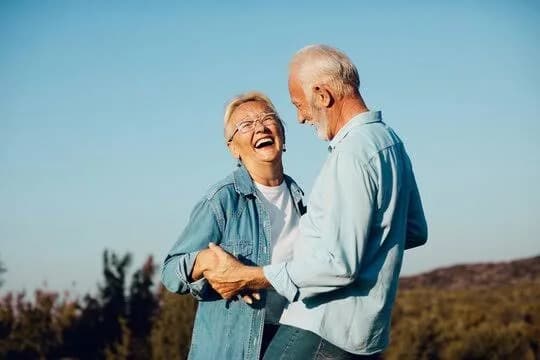 A senior couple laughing and dancing outdoors