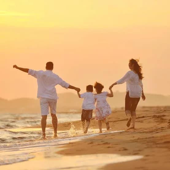 A young family running together along the beach at sunset